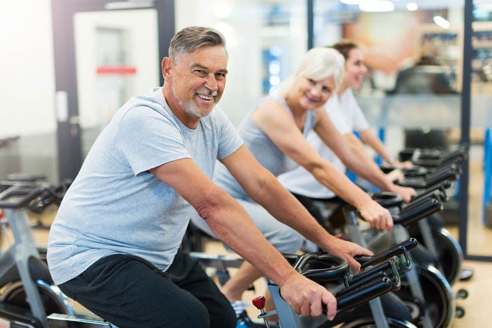 Confident seniors on exercise bikes in spinning class at gym