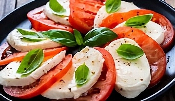 Mozzarella slices and tomato slices with leaves as garnish on top.