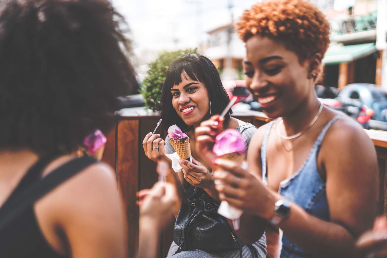 Group of people standing outside in a neighborhood eating ice cream and smiling.