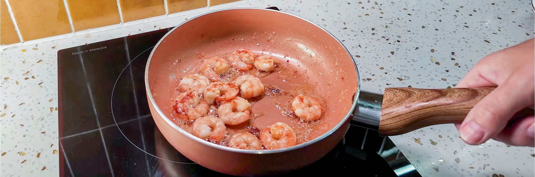 Overhead view of a frying pan with seasoned shrimp.
