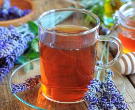 Glass mug of herbal bedtime latte tea with lavender and honey on a wooden surface.