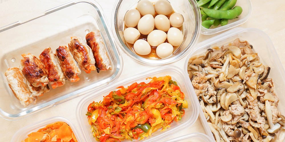 Assorted meal prep containers with grilled chicken, quail eggs, edamame, and mixed vegetable stir-fry.