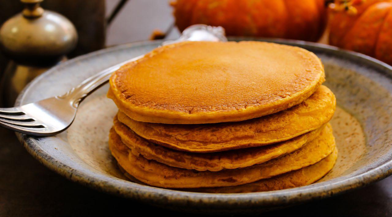 Stack of pancakes on a plate with a fork next to them.