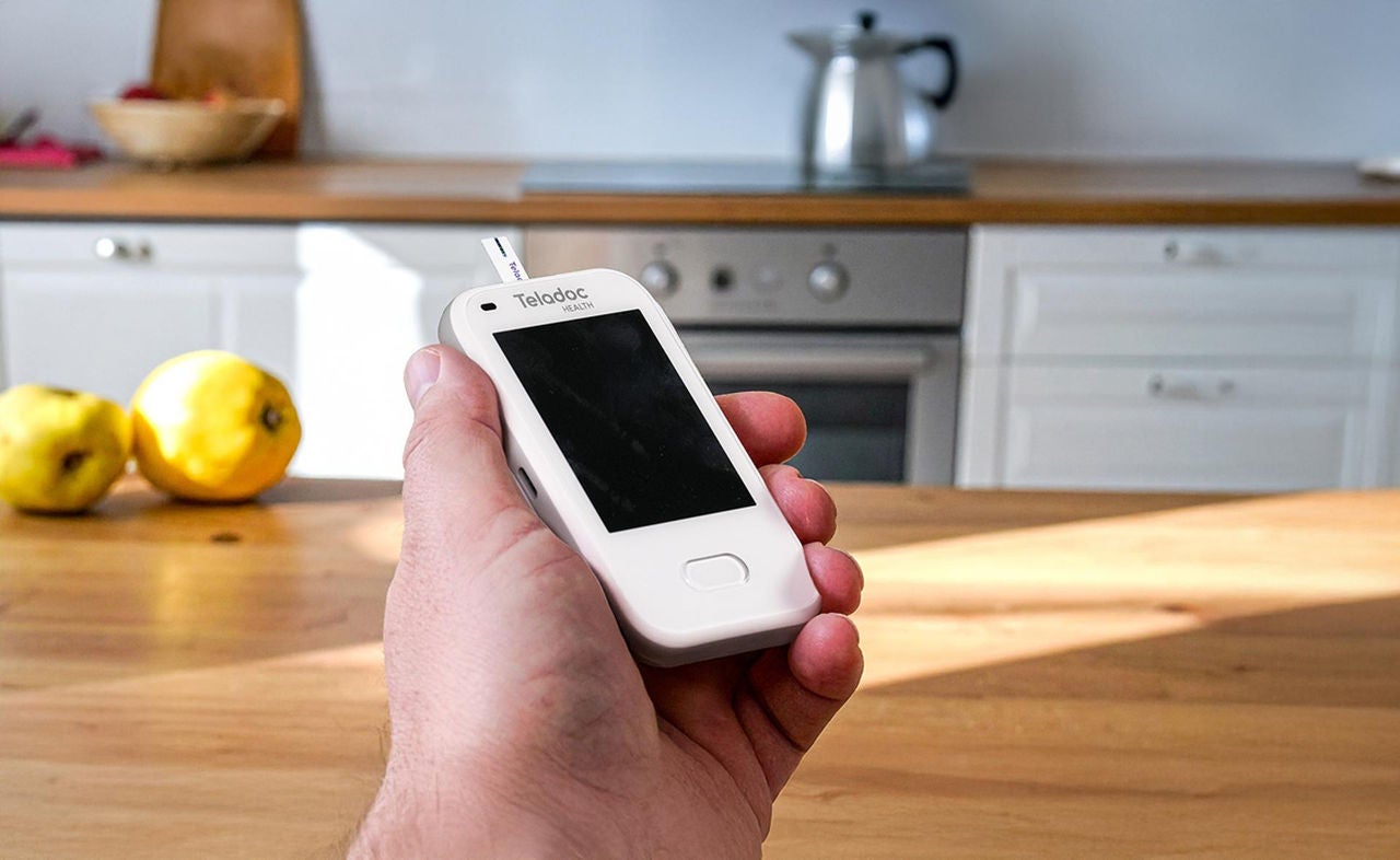 Hand holding a Teladoc blood glucose meter.