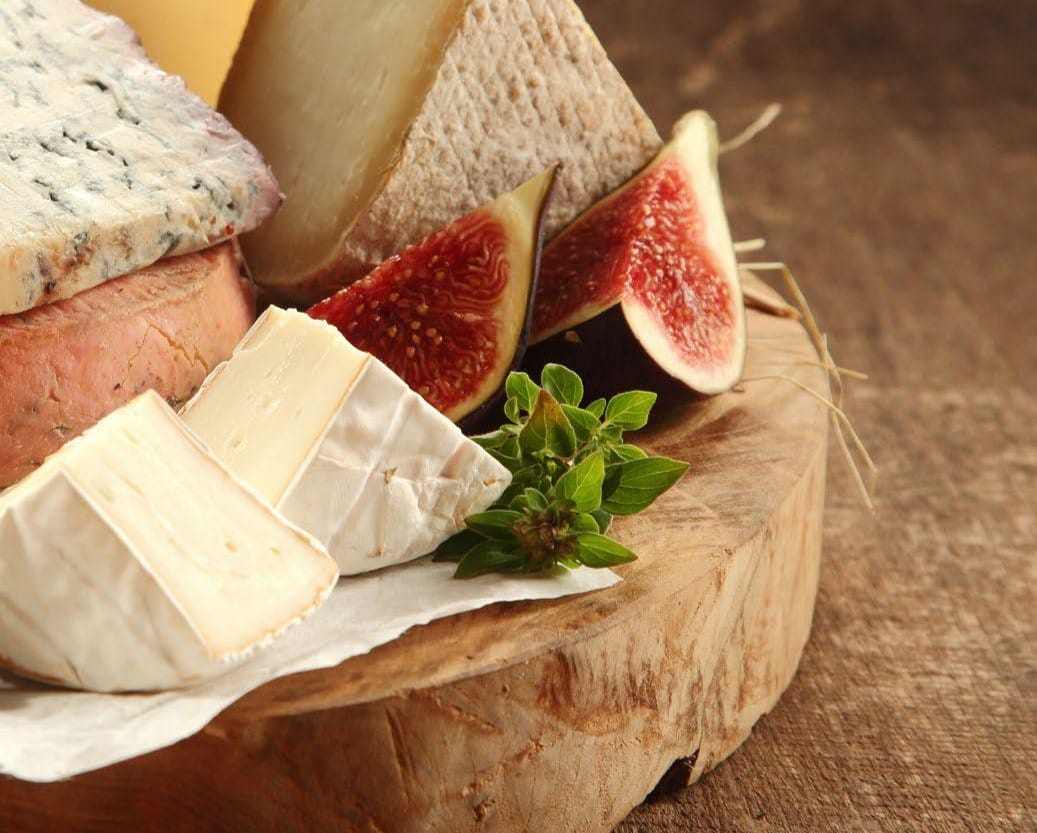 Assortment of cheeses on a round wooden block sitting on a table.
