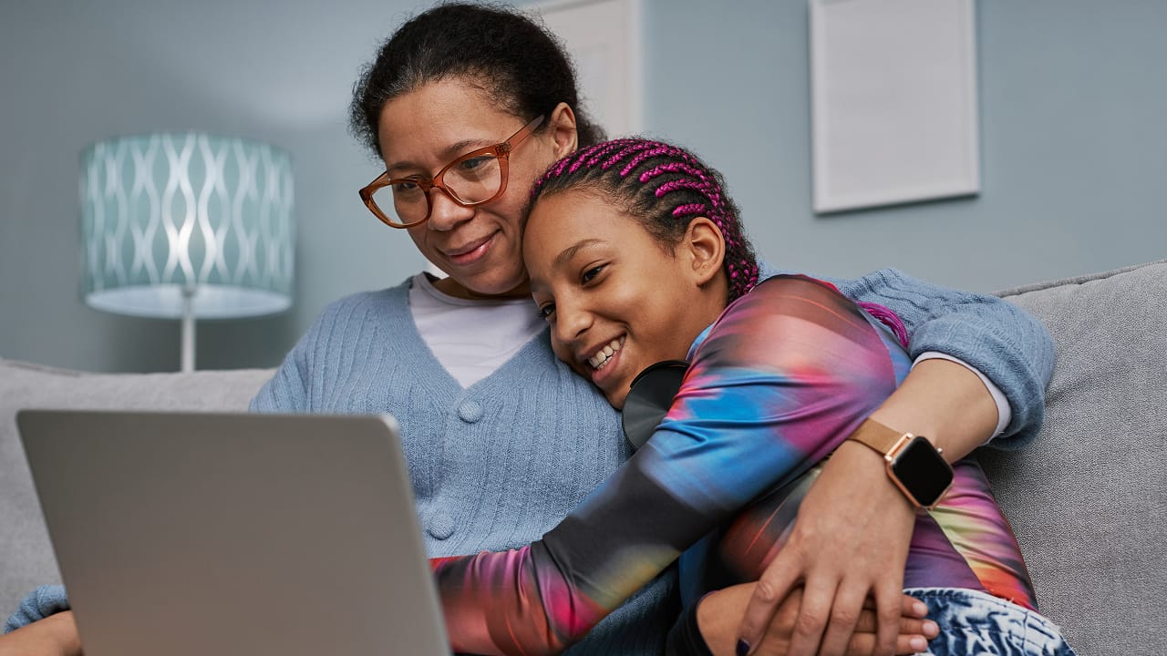 Mother and daughter smiling while looking at a computer