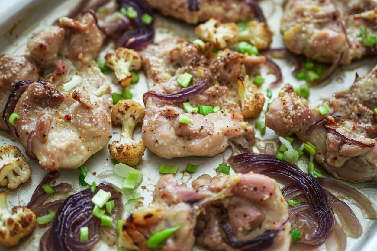 Plate with chicken thighs and cauliflower with seasonings and herbs.