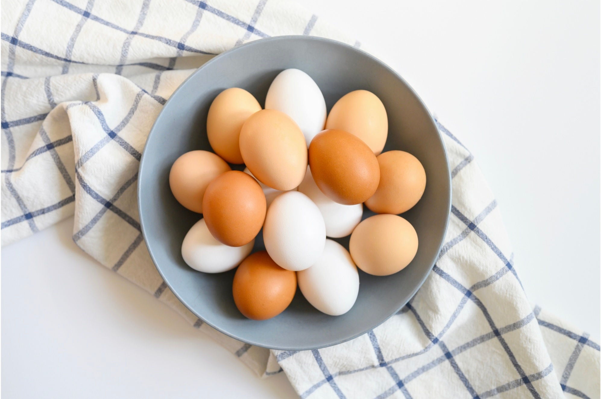 Bowl of white and brown eggs on a blue and white dish towel.