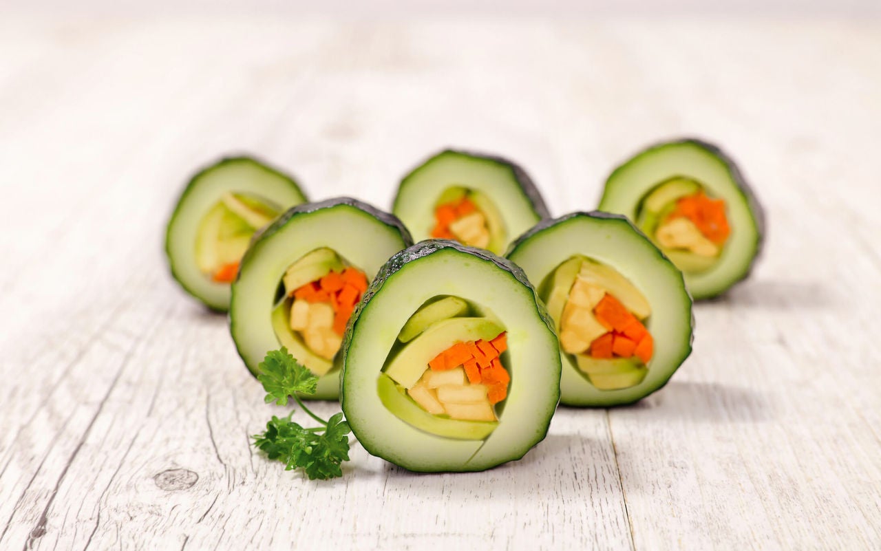 Sushi rolls with avocado, carrots and bell peppers with cucumber slices instead of rice and seaweed.