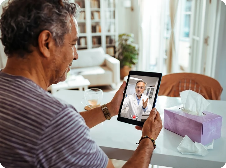  Man attending a virtual healthcare appointment on a tablet from home.