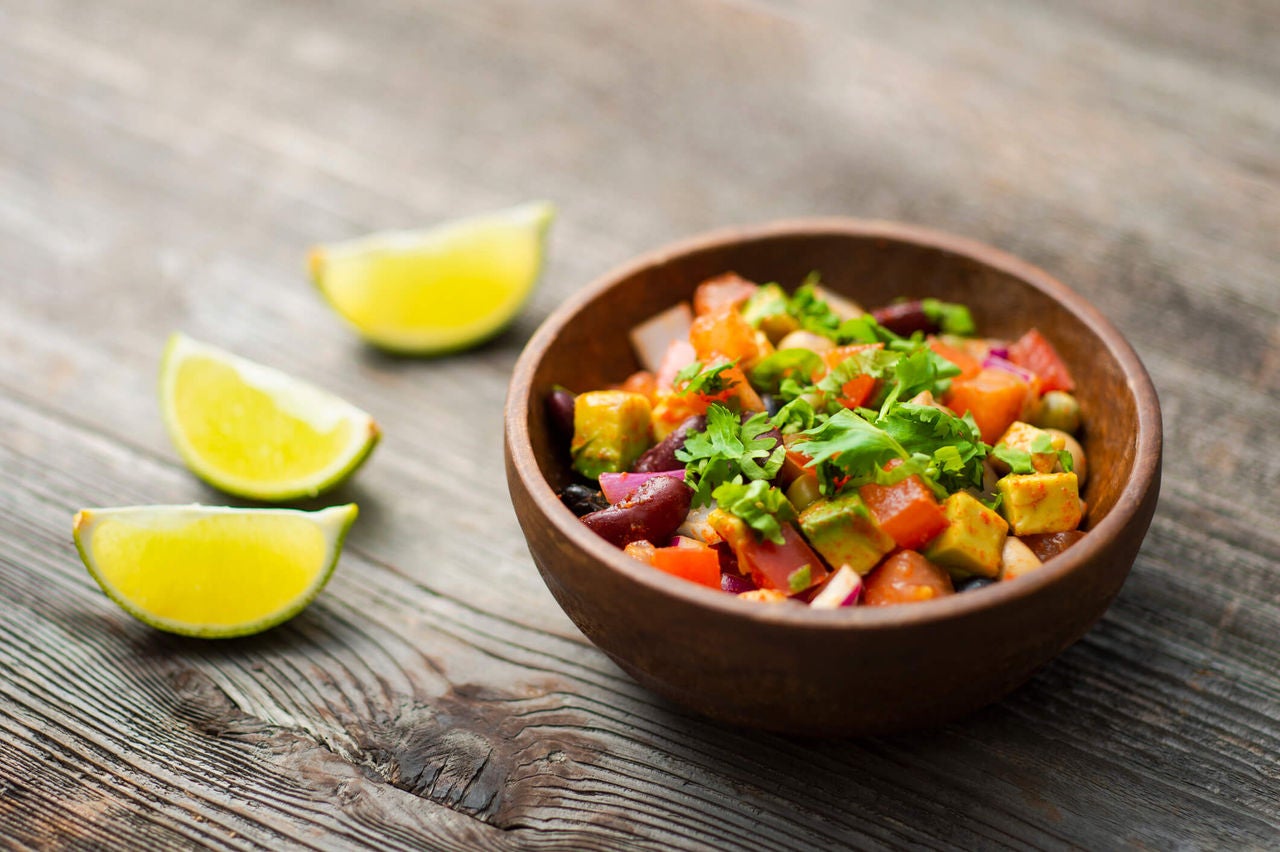 Bowl with chopped avocado, tomato and beans.