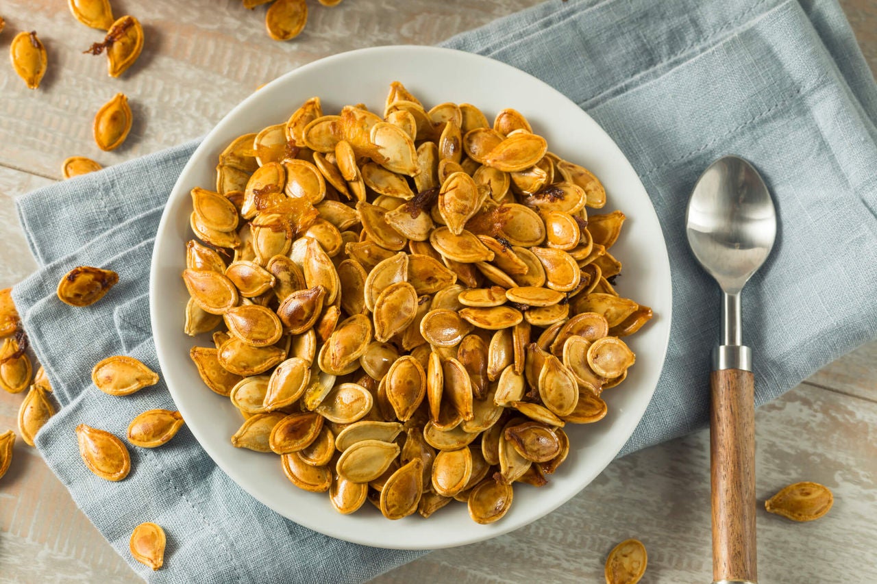 Seasoned pepitas in a bowl with a napkin and spoon.