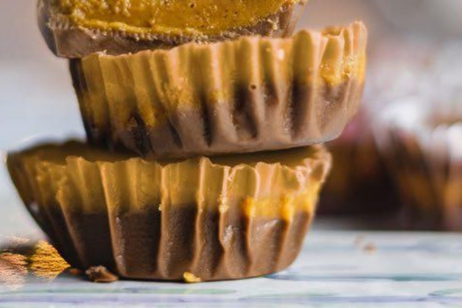 Dark chocolate peanut butter bites in a stack on a counter with more in the background.