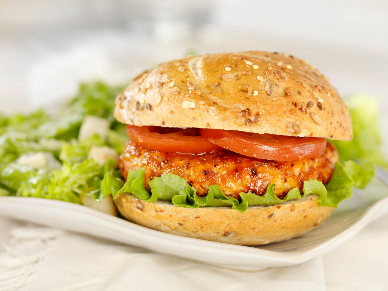 Turkey burger on a whole wheat bun with tomatoes and lettuce.