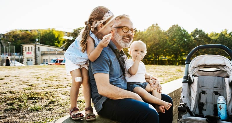 Dad and kids enjoying healthy snacks at park.