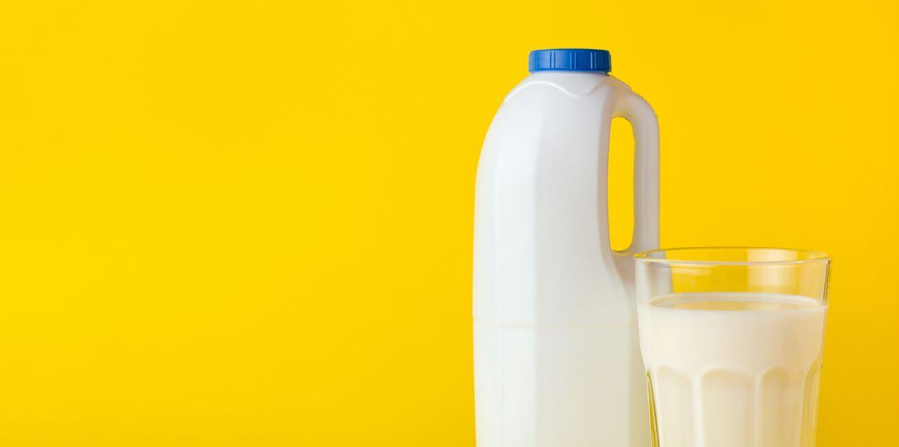 Bottle and glass of milk in a yellow background