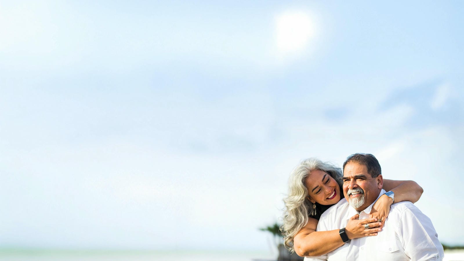Older couple smiling and embracing outdoors.