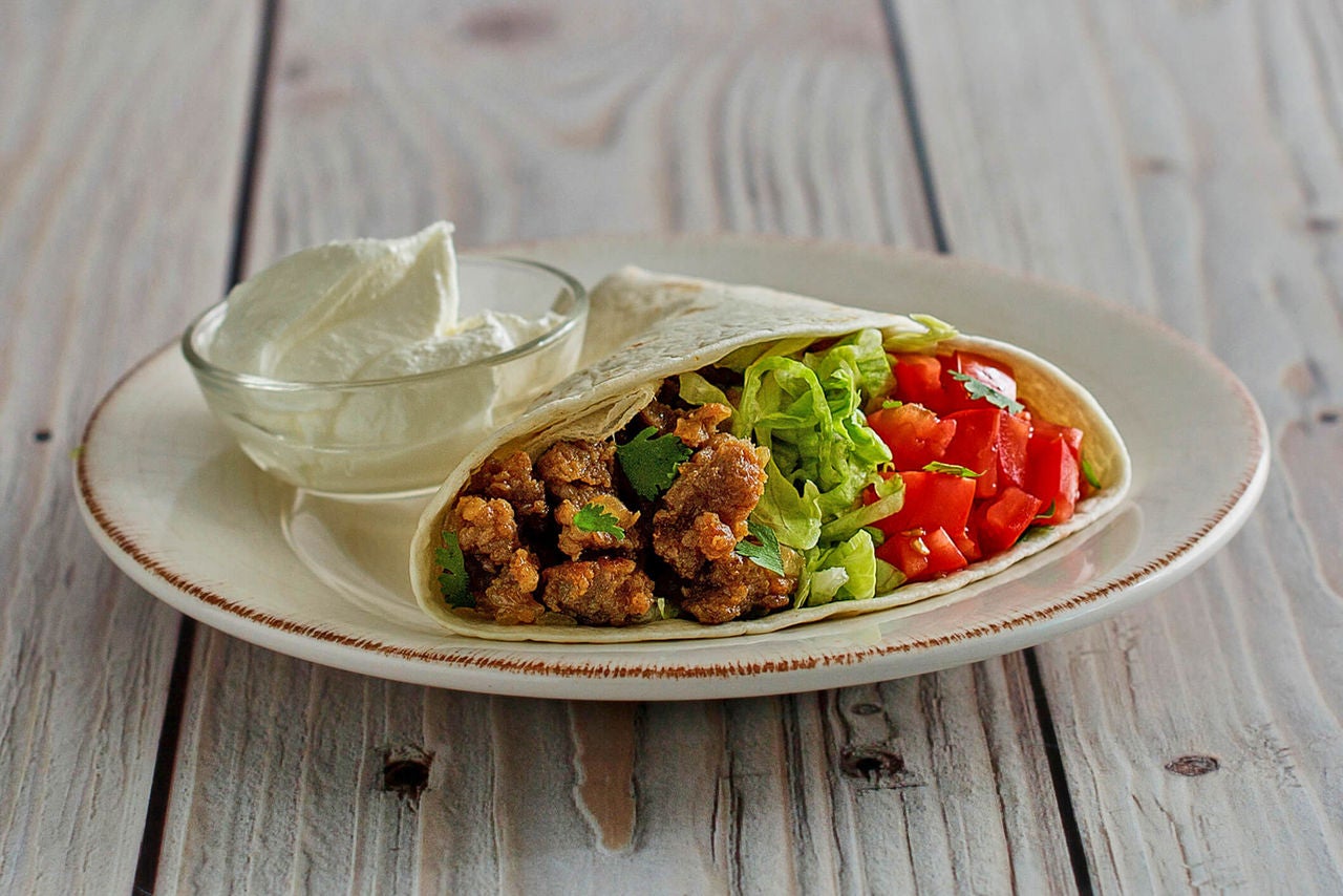 Taco with ground turkey, lettuce and tomatoes with a cup of Greek yogurt on the side.