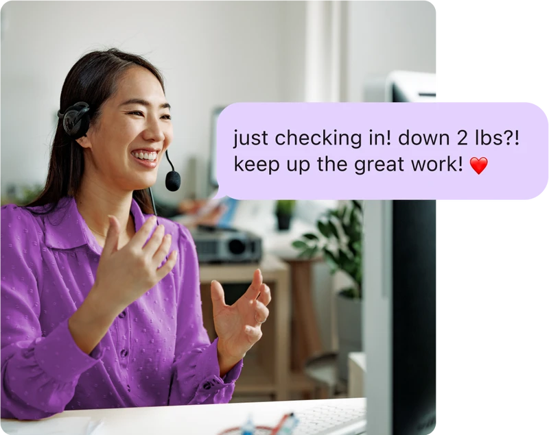 Woman with a headset smiling and talking to her computer, with an overlay of a coaching message reading 'Just checking in! Down 2 lbs?! Keep up the great work!'