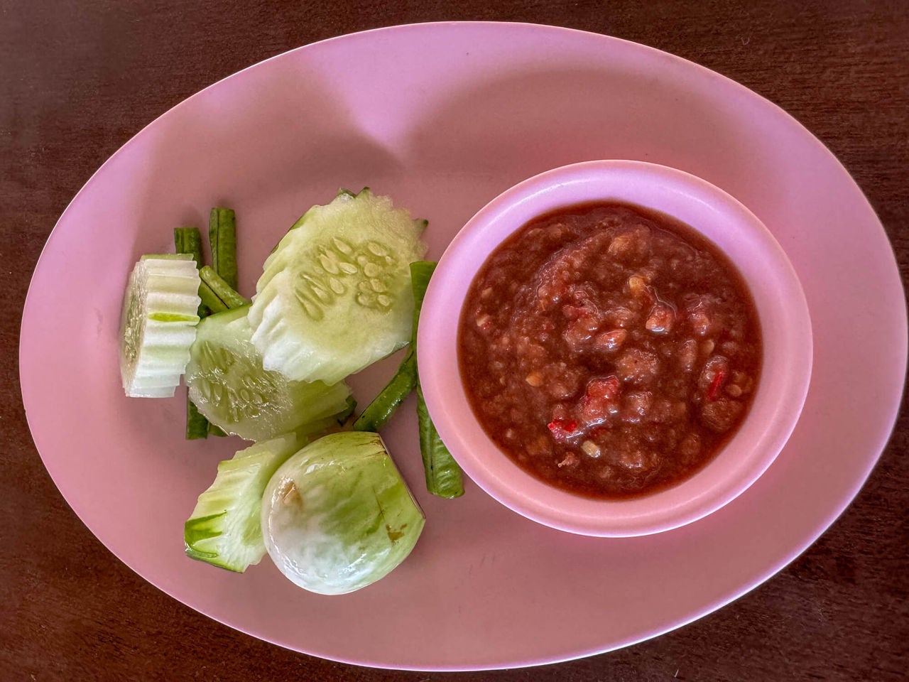 Bowl of salsa with sliced cucumbers on a plate. 
