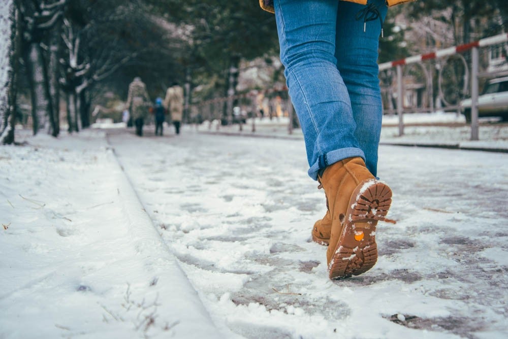 woman walking in winter city road, boots close up