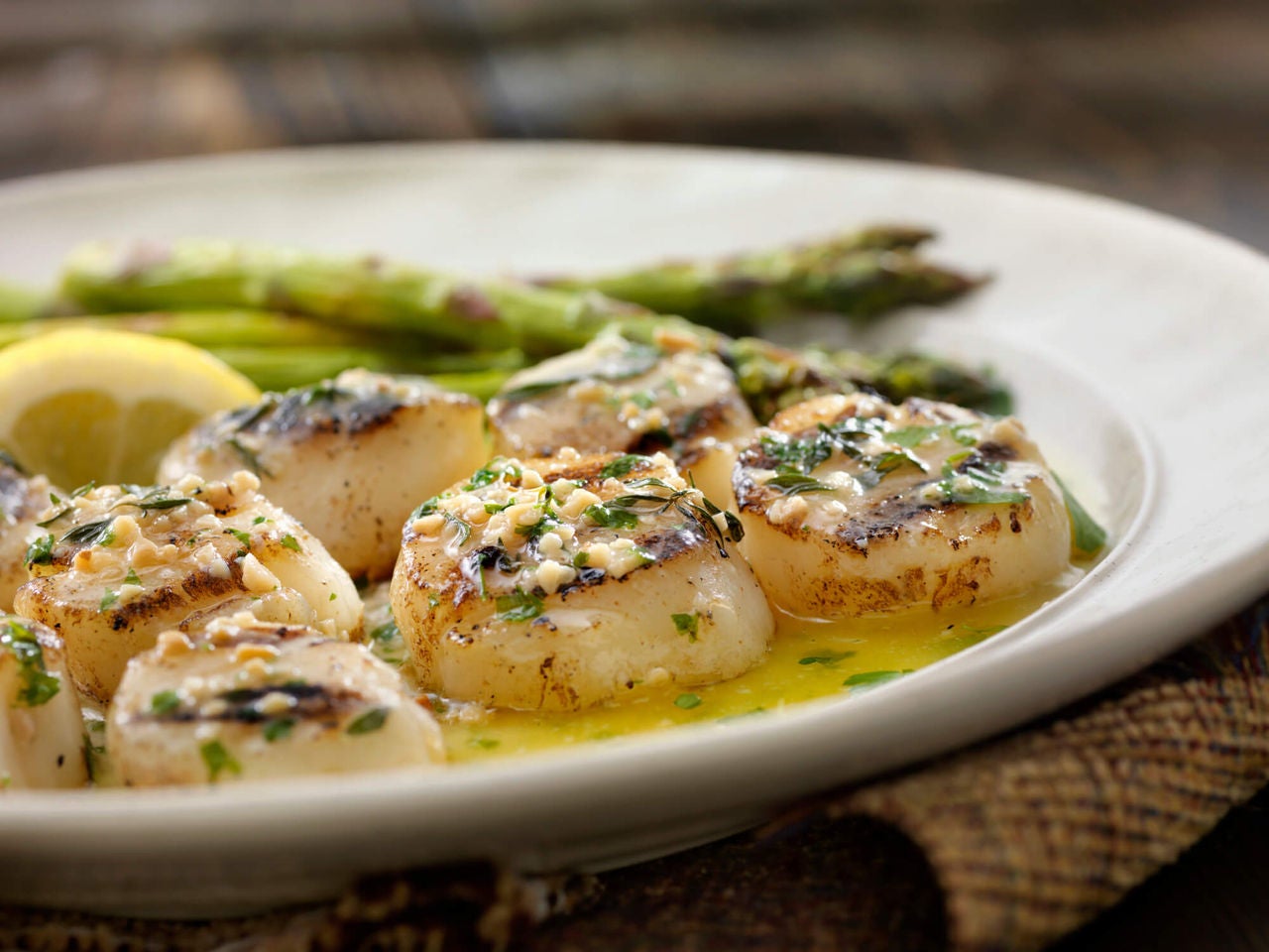 Seared scallops in a green sauce with asparagus spears.