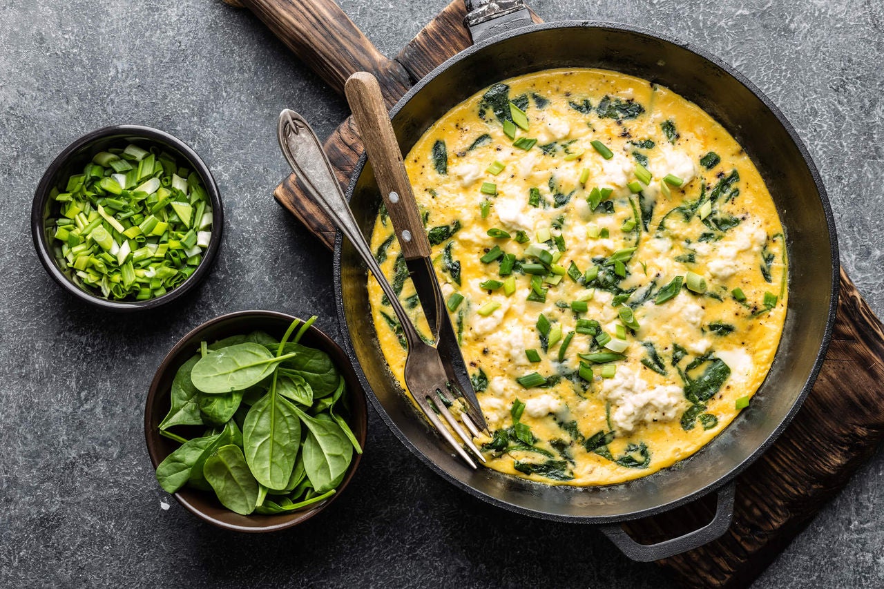 Egg frittata with cheese and spinach in a skillet.