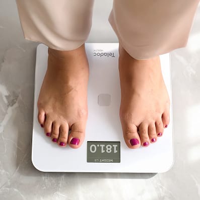 Close-up of bare feet standing on a Teladoc Health smart scale.