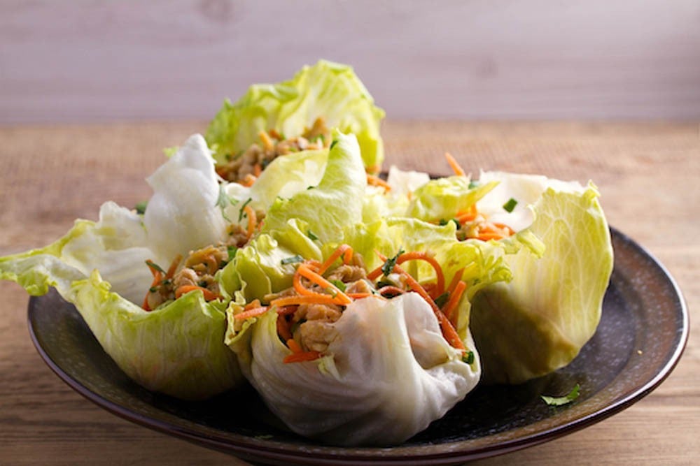 Wraps de pollo y lechuga en plato marrón sobre tabla de madera