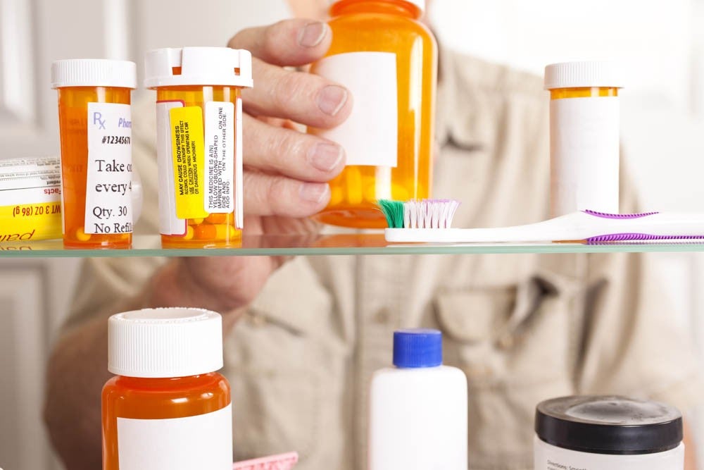 Hombre sacando pastillas recetadas del botiquín de medicamentos