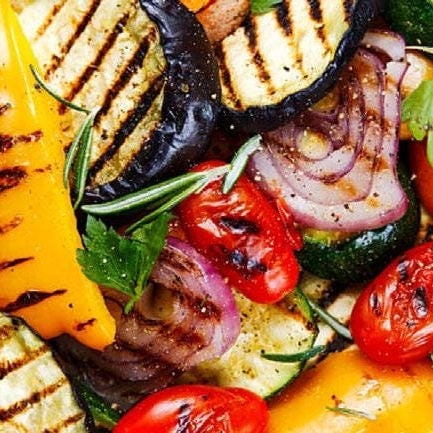 Grilled vegetables including onions, cherry tomatoes, yellow peppers