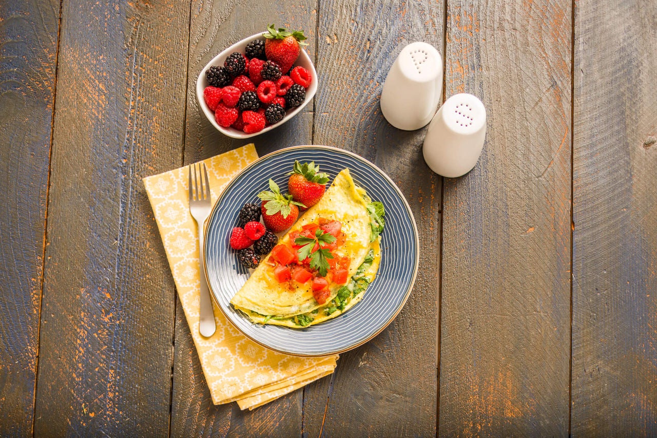 Omelet with greens and tomatoes, with a side of berries.
