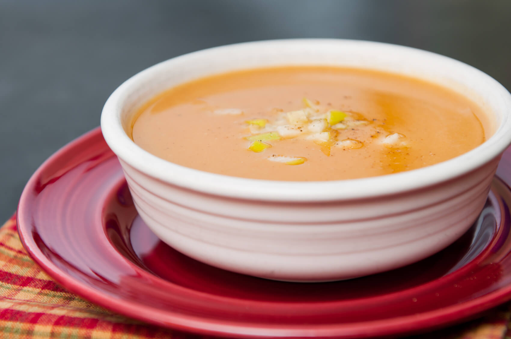 Bowl of squash soup topped with apple pieces and black pepper.