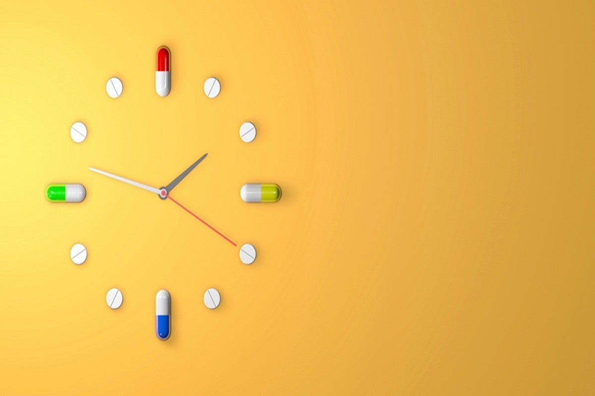 Clock made of pills and capsules on a yellow background, symbolizing medication schedule