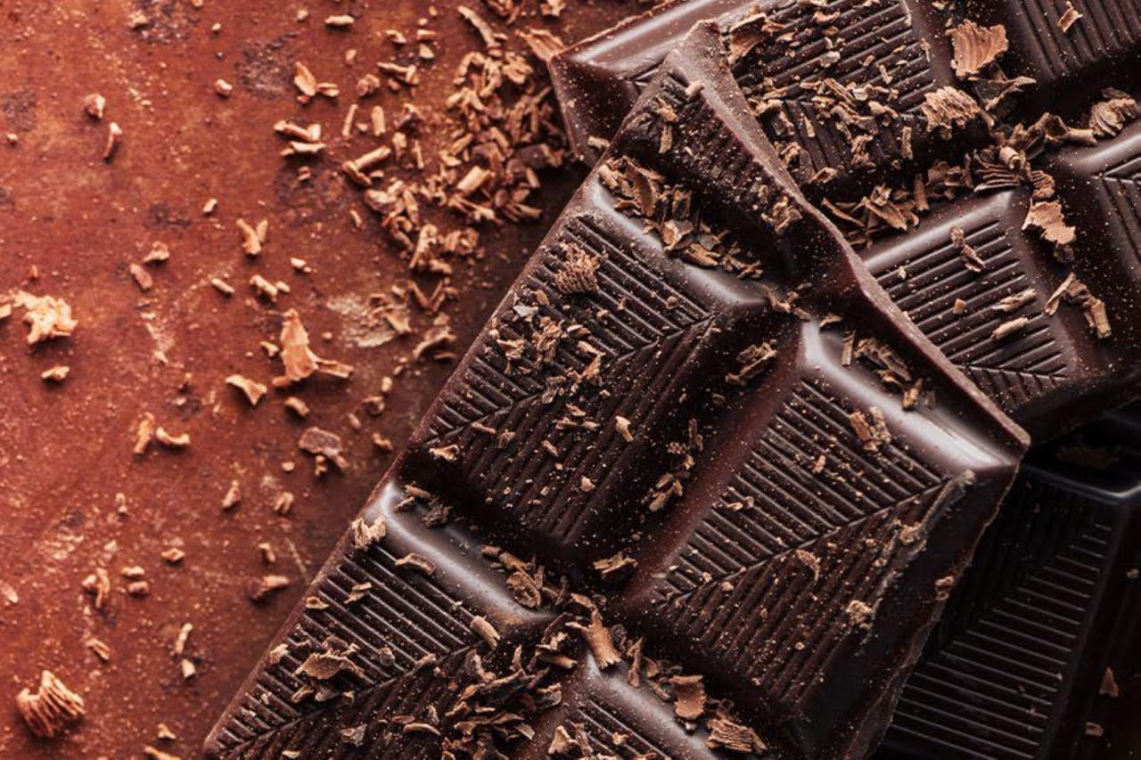 A chocolate bar placed on a vibrant red background, highlighting its rich color and texture.