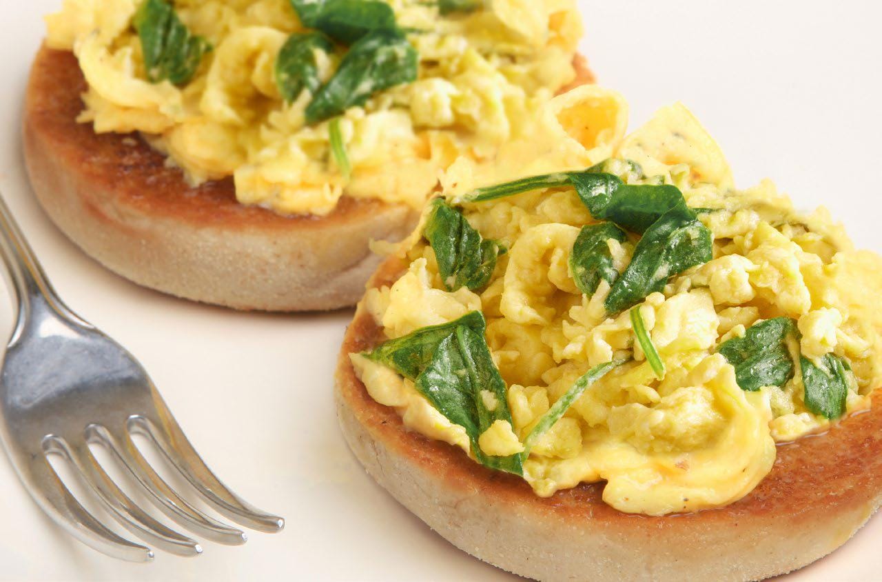 Eggs with spinach on English muffin with a fork on the side