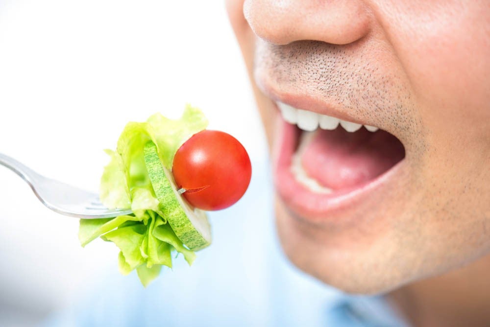 Young man eating healthy salad, close up