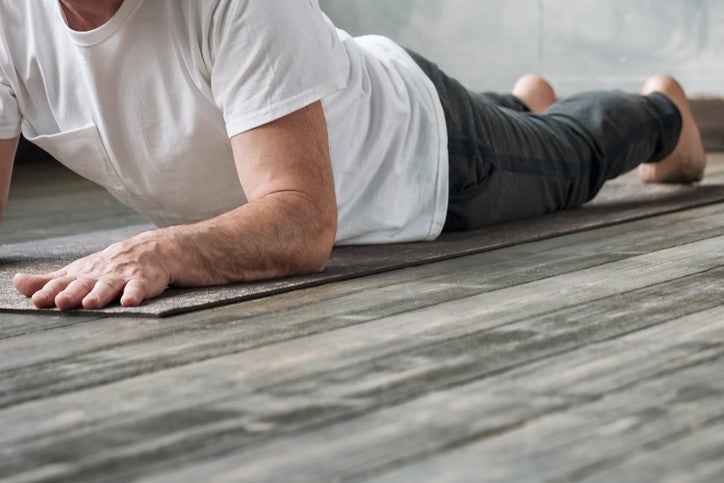 Yoga man in Cobra or sphinx pose bhujangasana variation in the gym. No face view.