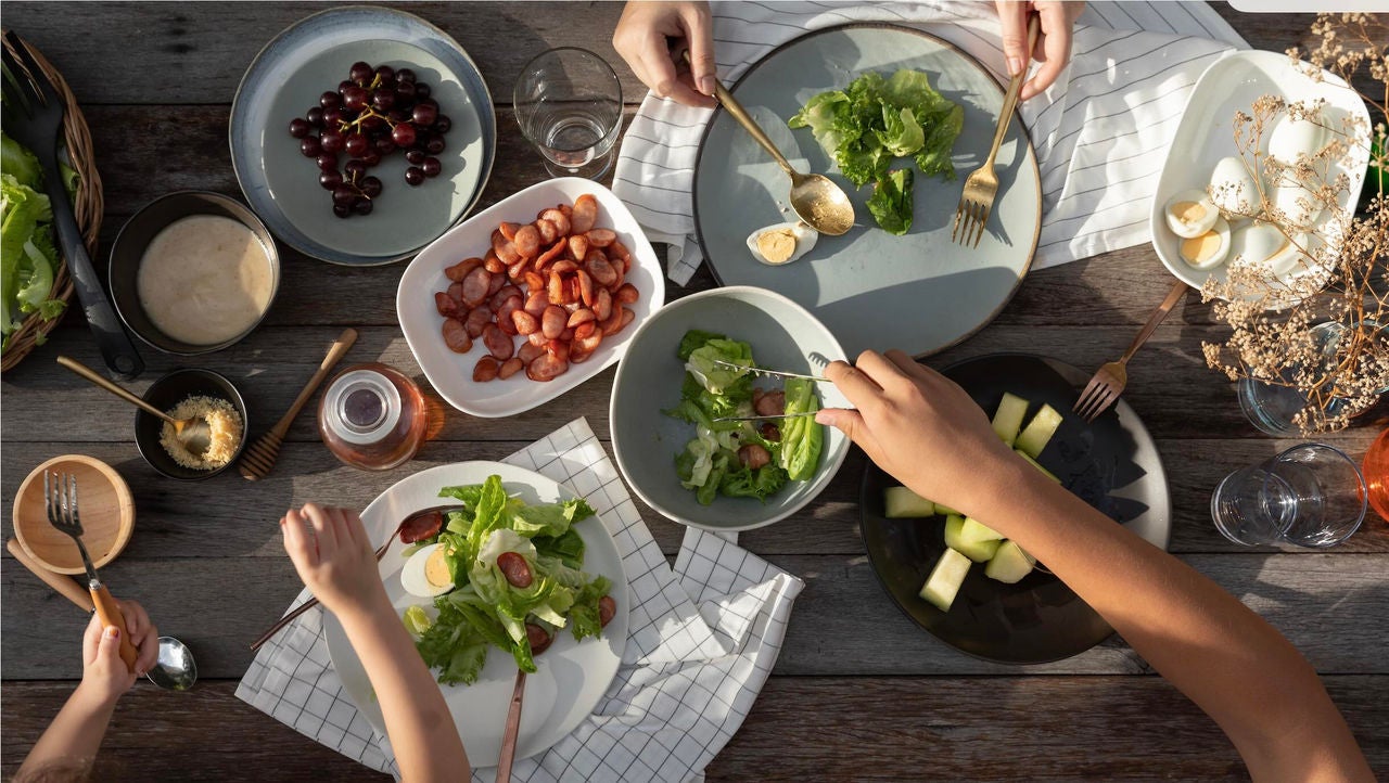 Overhead view of people around a table serving portions of various dishes.