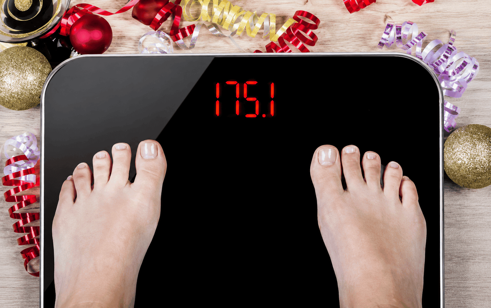 Feet on a scale with holiday decorations in the background.