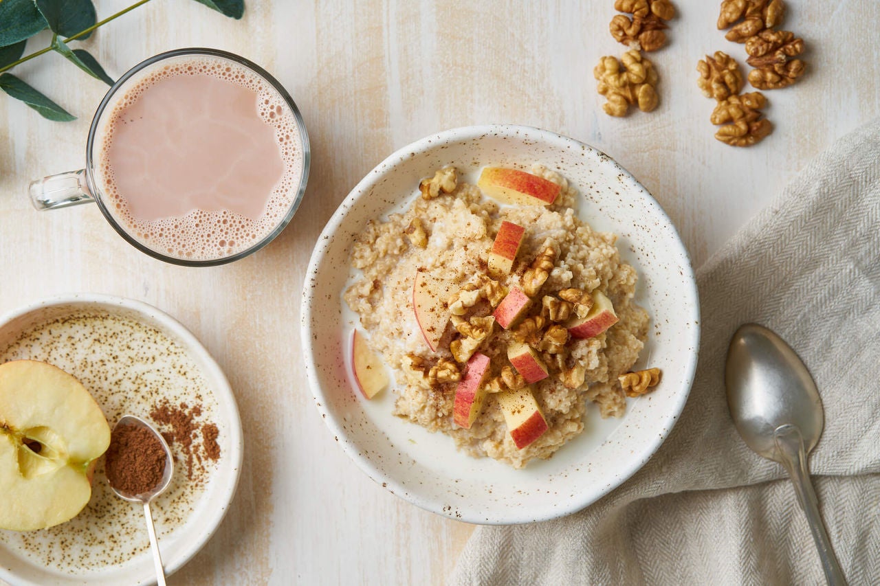 Bowl of oatmeal with walnuts and chopped apples on top. 