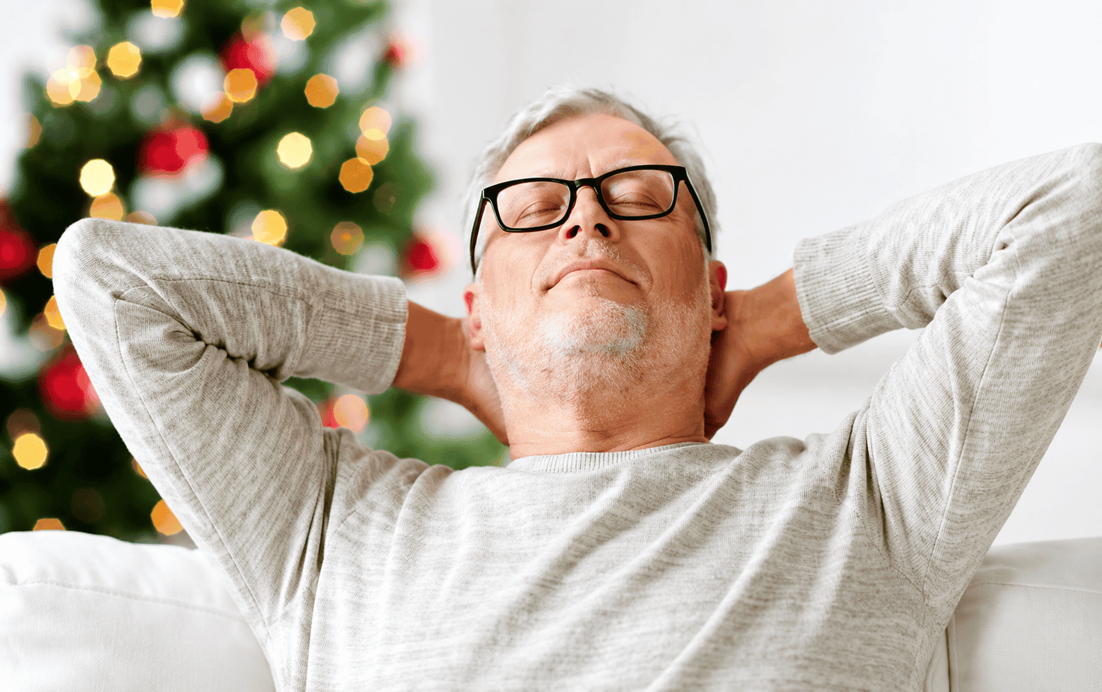 Man resting on couch with Christmas tree in the background