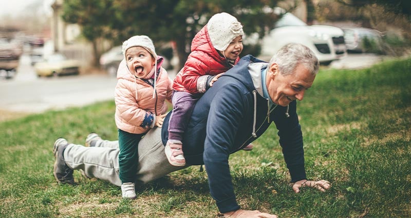 Grandpa doing pushups with littles on his back.