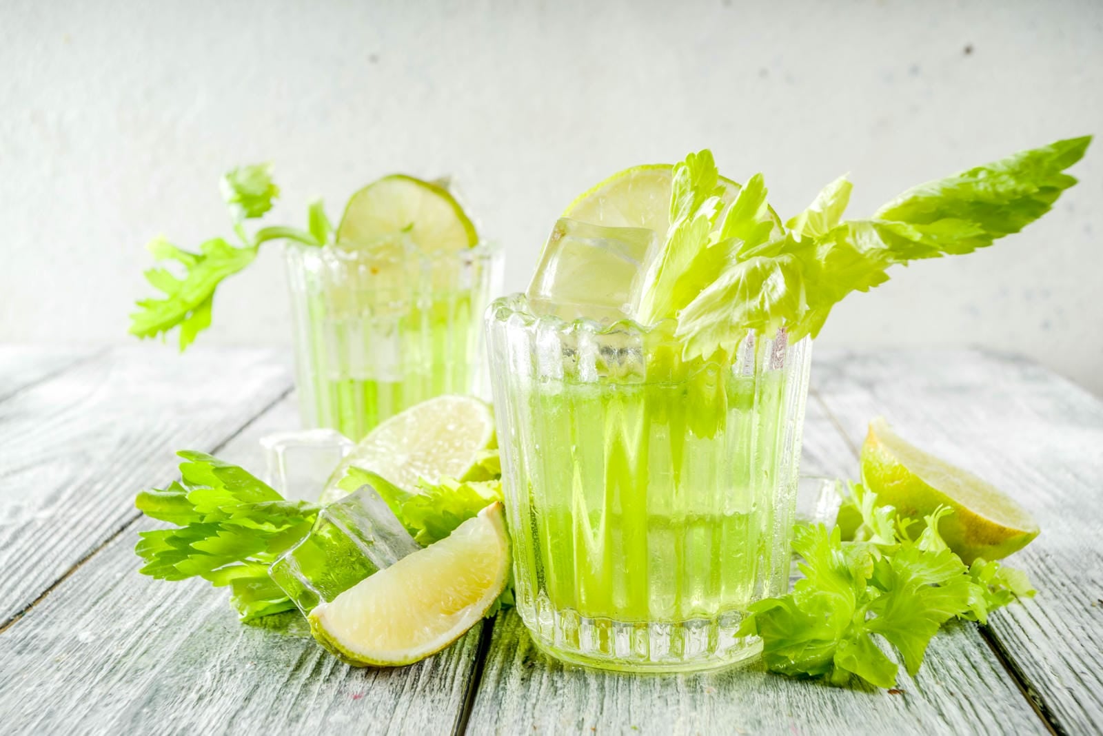 Celery Daisy Cocktail. Fresh summer drink, mojito, iced lemonade or margarita with celery and lime slices, wooden background copy space