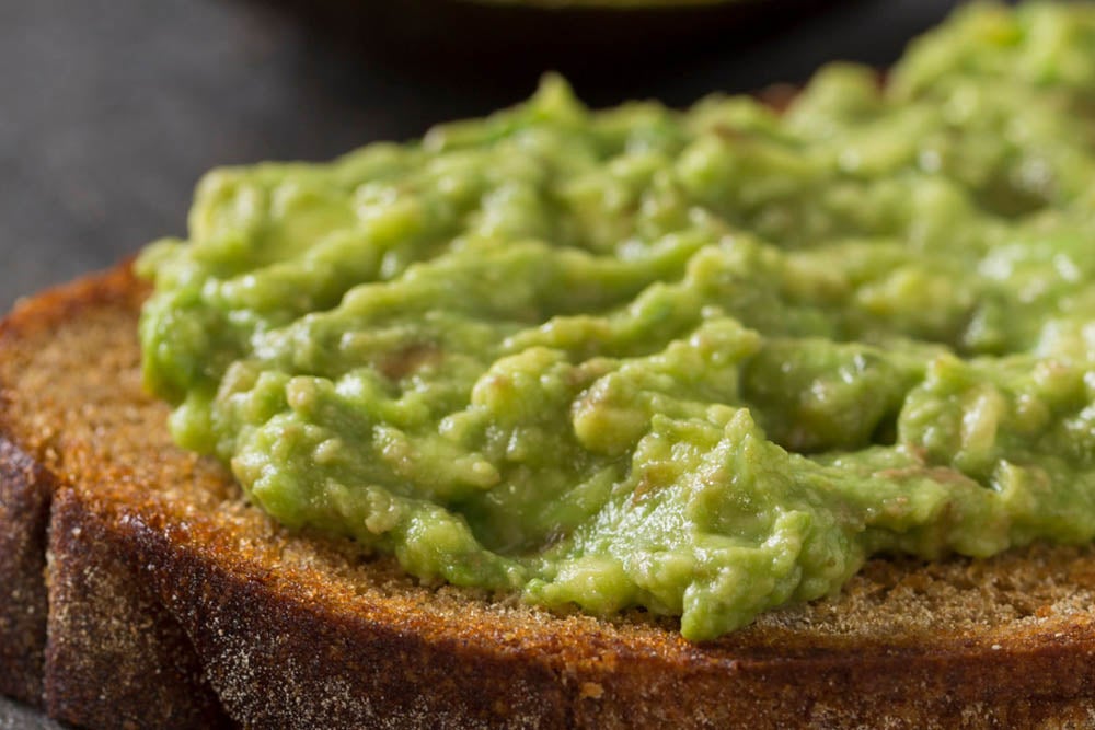 Close-up of mashed avocado spread on a slice of whole grain toast