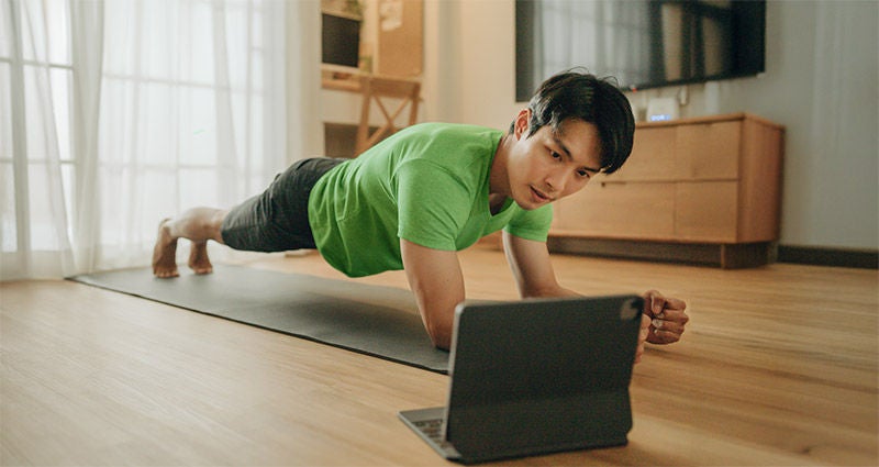 Man doing a plank in front of computer. 