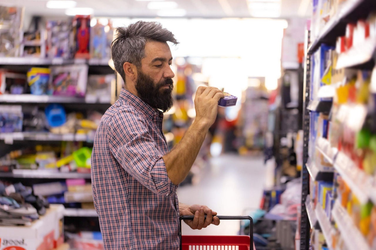 Man examining a product in a grocery store aisle.