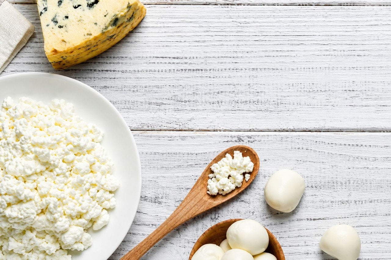 Cottage cheese, mozzarella, and blue cheese arranged on a white wooden table.