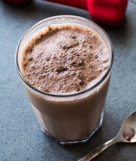 Protein shake in a glass on a grey counter with a spoon next to it