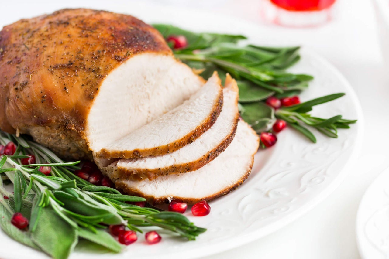 Sliced roast turkey with sprigs of rosemary and pomegranite arils. 